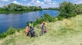 Family on bikes cycling outdoors, active parents and kids on bicycles, aerial view of happy family with children relaxing