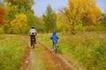 Family on bikes in golden autumn park, father and kids cycling on trail, active sport with children