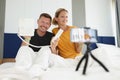 Family of bloggers hold push-button phone and shoot video camera hotel room Royalty Free Stock Photo