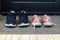 Family blue shoes and red sneakers on the rug at the front door