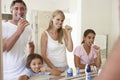 Family Brushing Teeth In Bathroom Mirror