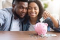 Family Budget. Happy Black Couple Putting Money To Piggybank At Home Royalty Free Stock Photo