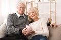 Family budget. Senior couple holding piggybank and looking at camera Royalty Free Stock Photo