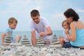 Family builds stone stacks on pebble beach Royalty Free Stock Photo