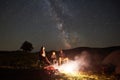 Family beside camp, campfire, tent under night starry sky