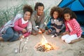 Family Camping On Beach And Toasting Marshmallows