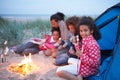 Family Camping On Beach And Toasting Marshmallows