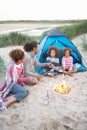 Family Camping On Beach And Toasting Marshmallows