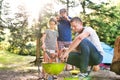 Family camping in forest, cooking meat on barbecue grill. Royalty Free Stock Photo