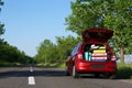 Family car with open trunk full of luggage on highway