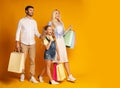 Family Carrying Colorful Shopping Bags Walking Over Yellow Background Royalty Free Stock Photo