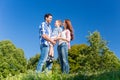 Family carrying kid, the parents standing on meadow