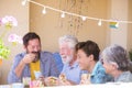 Family caucasian people with mixed generations and years age have fun together eating fast food hamburger like lunch at home - Royalty Free Stock Photo