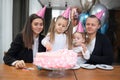 Family celebrates daughter& x27;s birthday. A man, a woman and two girls. Festive decor, cake, sweets, balloons. Daughters