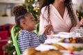 Family Celebrating Christmas At Home With Mother And Daughter Saying Prayer Before Eating Meal 