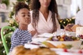 Family Celebrating Christmas At Home With Mother And Daughter Saying Prayer Before Eating Meal 