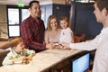 Family Checking In At Hotel Reception Desk