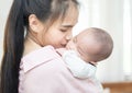 Family, child and parenthood concept - happy beautiful young asian mother smiling hugging holding newborn baby in her arms at home Royalty Free Stock Photo