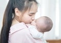 Family, child and parenthood concept - happy beautiful young asian mother smiling hugging holding newborn baby in her arms at home Royalty Free Stock Photo