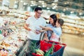 Family with child and shopping cart buying food at grocery store or supermarket Royalty Free Stock Photo