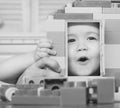 Family and childhood concept. Kid looking through door of toy house made of plastic blocks. Child plays with