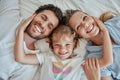 Family, children and face with a girl, mother and father lying on a bed together in their home in the morning. Portrait Royalty Free Stock Photo