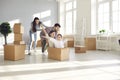 Happy family having fun and playing with cardboard boxes in their newly bought house