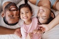 Family, children and love with a girl and parents lying on the bed in a bedroom of their home together from above. Kids Royalty Free Stock Photo