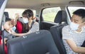 Family with children rides in car and mother help child wear medical mask