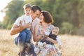 Family with children walking outdoors in summer field at sunset. Father, mother and two children sons having fun in Royalty Free Stock Photo