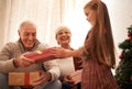 Family, christmas giving and gifts with kids and grandparents together with tree in living room. Home, happy and present Royalty Free Stock Photo