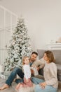 Family Christmas morning in a bright minimalistic living room near the Christmas tree. Royalty Free Stock Photo