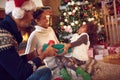 Family on Christmas opening gifts sitting on floor at home