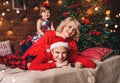 Family in Christmas Santa hats lying on bed. Mother, father and baby having fun in living room decorated by Christmas tree Royalty Free Stock Photo