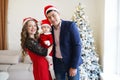 Family in Christmas Santa hats near christmas tree. Mother, father and baby having fun at home. Winter holiday Xmas and New Year Royalty Free Stock Photo