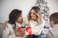 Family Christmas traditions. Grandma, mother and child exchanging xmas gifts at home