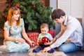 Family, christmas, x-mas, winter, happiness and people concept - smiling family with baby boy sitting under xmas tree Royalty Free Stock Photo