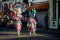 Family in colorful carnival elephant costumes walk by city street at dominican parade