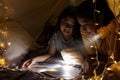 Family concept. elder sister and sister reading book with flashlight together before bedtime. Sister read story book together in Royalty Free Stock Photo