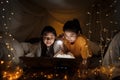 Family concept. elder sister and sister reading book with flashlight together before bedtime. Sister read story book together in Royalty Free Stock Photo