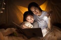 Family concept. Mother and child daughter reading book with flashlight together in children tent before bedtime. Happy mother read Royalty Free Stock Photo