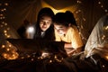 Family concept. Mother and child daughter reading book with flashlight together in children tent before bedtime. Happy mother read Royalty Free Stock Photo