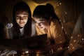 Family concept. Mother and child daughter reading book with flashlight together in children tent before bedtime. Happy mother read Royalty Free Stock Photo