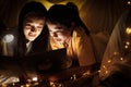 Family concept. Mother and child daughter reading book with flashlight together in children tent before bedtime. Happy mother read Royalty Free Stock Photo