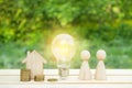 Family concept. Wooden house, lightbulb and many little men on a wooden table. Energy saving, debts for utility bills. Copy space Royalty Free Stock Photo