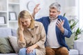 Family conflict quarrel, man shouting and upset woman close-up, couple sitting on sofa in living room Royalty Free Stock Photo