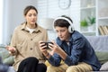 Family conflict quarrel, woman mother quarrels with son, teenage boy in headphones ignores woman and plays video games Royalty Free Stock Photo