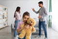 Family conflicts. Little girl suffering from parents quarrels, cuddling her teddy bear, feeling lonely and depressed Royalty Free Stock Photo