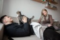 Young family couple with domestic cat and tea cup on sofa at home Royalty Free Stock Photo