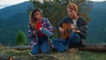 Family couple enjoy mountains on camping. Two travelers play guitar outdoors.